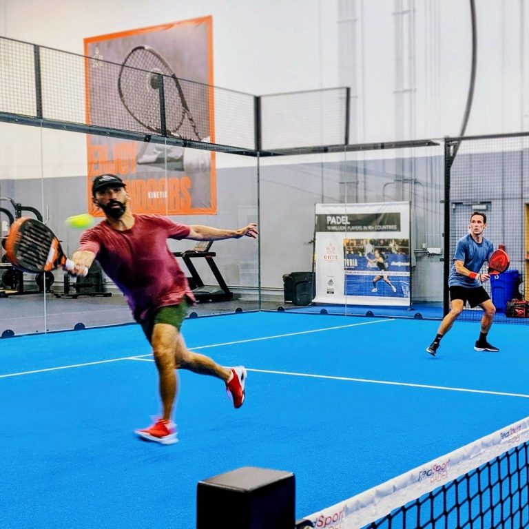 Match Play A player in red stretches out for a forehand volley as his partner watches on