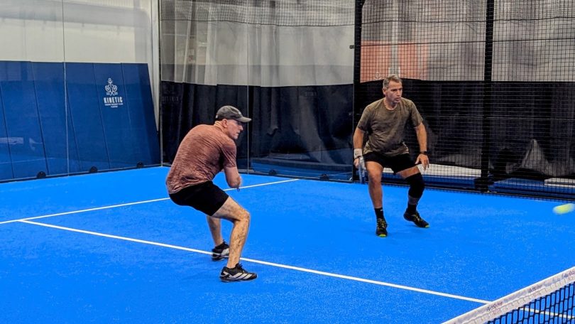 Dealing with a chiquita! Two padel players prepare to deal with a low ball to their feet.